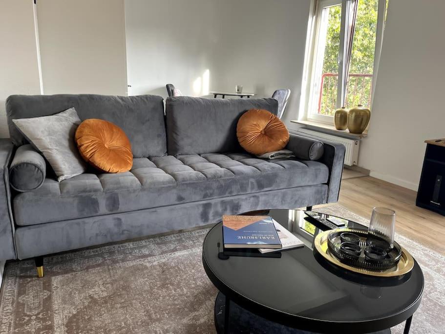 sala de estar con sofá gris con almohadas y mesa en City Appartement direkt am Schloss! en Karlsruhe