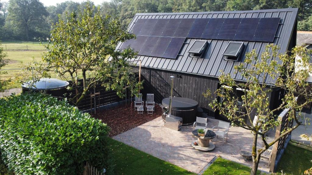 un patio trasero con una casa con paneles solares. en B&B Het Zwarte Schaap en Albergen