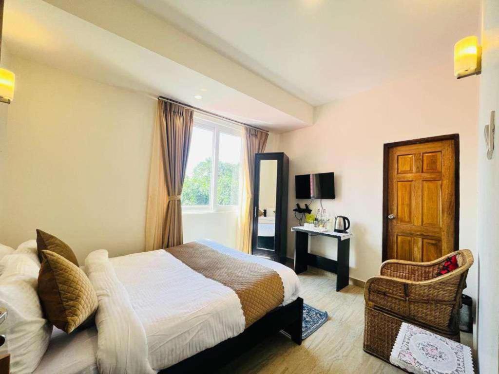 Un dormitorio con una cama y una ventana y una silla. en Maplewood Hotel & Spa, en Gangtok