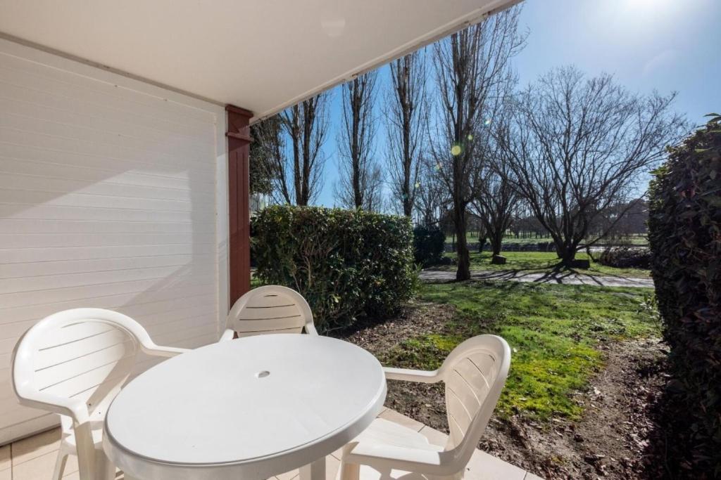 une table et des chaises blanches assises sur une terrasse couverte dans l'établissement Résidence Port Bourgenay - maeva Home - Appartement 2 pièces 5 personnes - Sélection MAE-6356, à Talmont-Saint-Hilaire