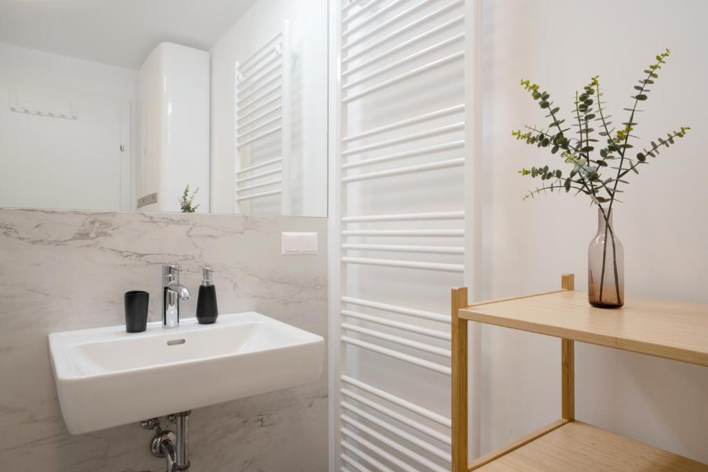 bagno bianco con lavandino e specchio di easy flat Villach main plaza a Villach