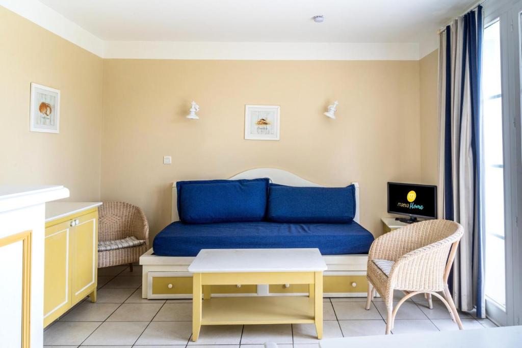 un salon avec un canapé bleu et une table dans l'établissement Les Maisons de Port Bourgenay - maeva Home - Maison 3 Pièces 6 Personnes - Sélection MAE-2694, à Talmont-Saint-Hilaire