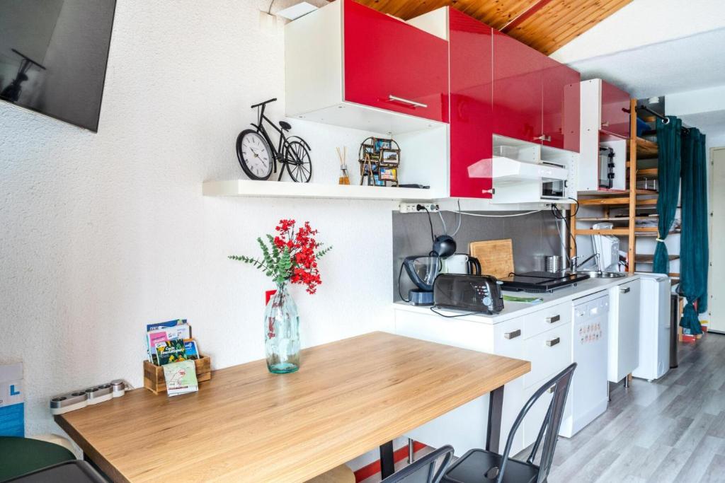 une cuisine avec des placards rouges et une table en bois dans l'établissement Résidence Port Bourgenay - maeva Home - Appartement 2 pièces pour 4 personnes - Sélection MAE-5574, à Talmont-Saint-Hilaire