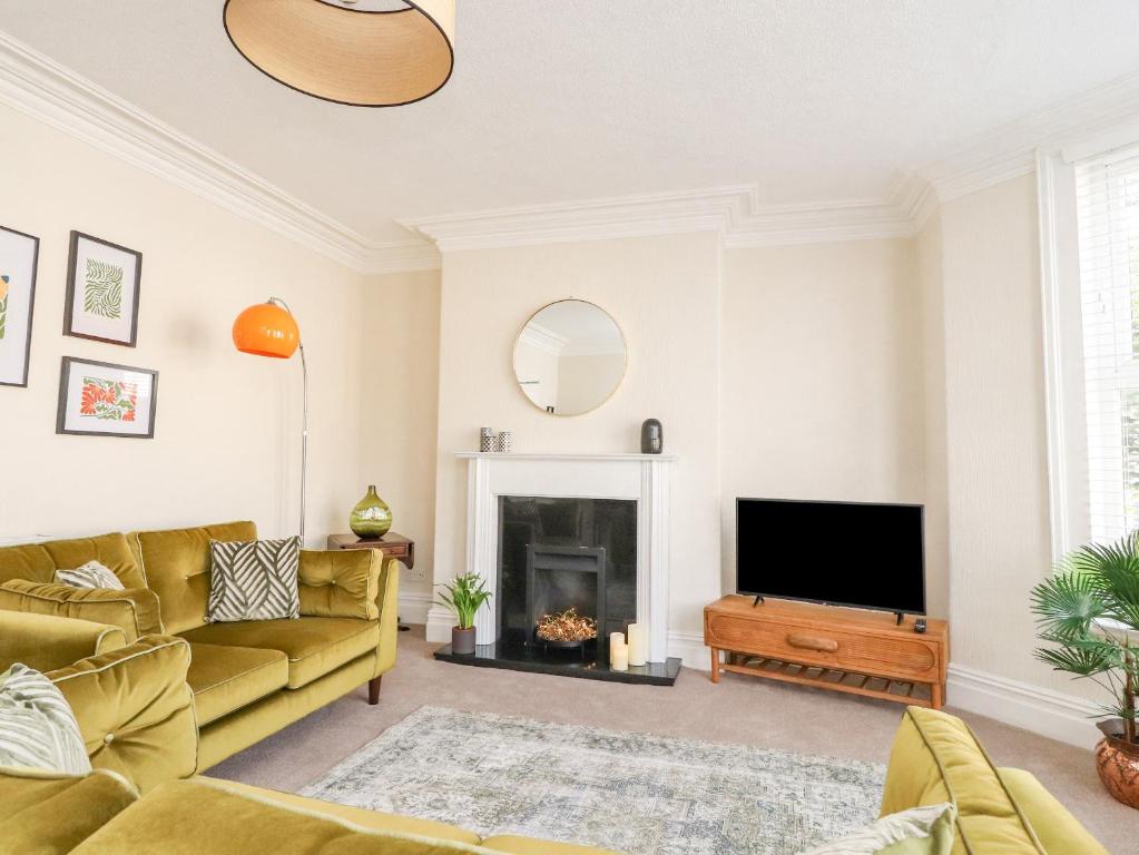 a living room with a yellow couch and a television at 53A Princes Crescent in Morecambe