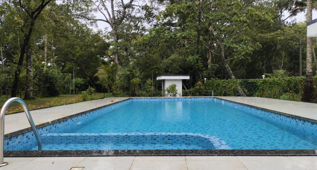 a swimming pool with blue water in a yard at Marari Beach Palace in Mararikulam