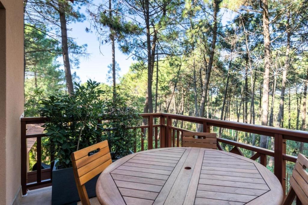 une table et des chaises en bois sur une terrasse avec des arbres dans l'établissement Résidence Lacanau Les Pins - maeva Home - Appartement 2 Pièces 4 Personnes - Prestige MAE-2614, à Lacanau