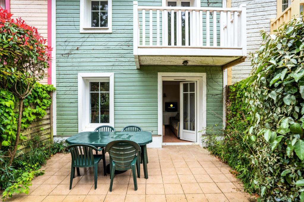 un patio avec une table et des chaises devant une maison dans l'établissement Les Maisons de Lacanau les Pins - maeva Home - Maison 3 Pièces 4 Personnes - Sélection MAE-2364, à Lacanau