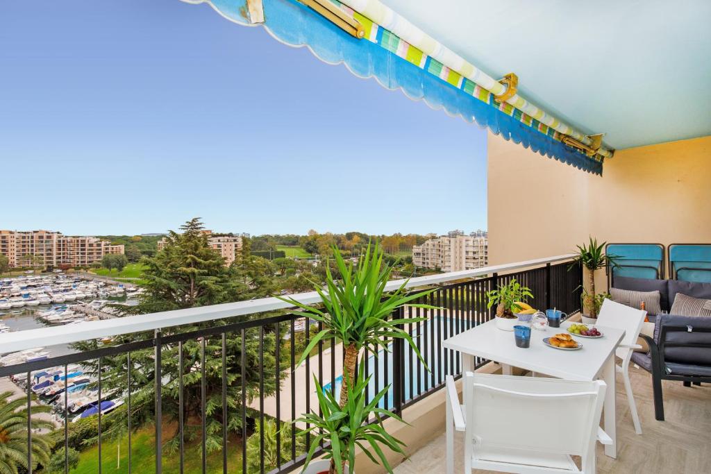 a balcony with a table and chairs and a view of a harbor at Appartement à 2 pas du golf in Mandelieu-la-Napoule