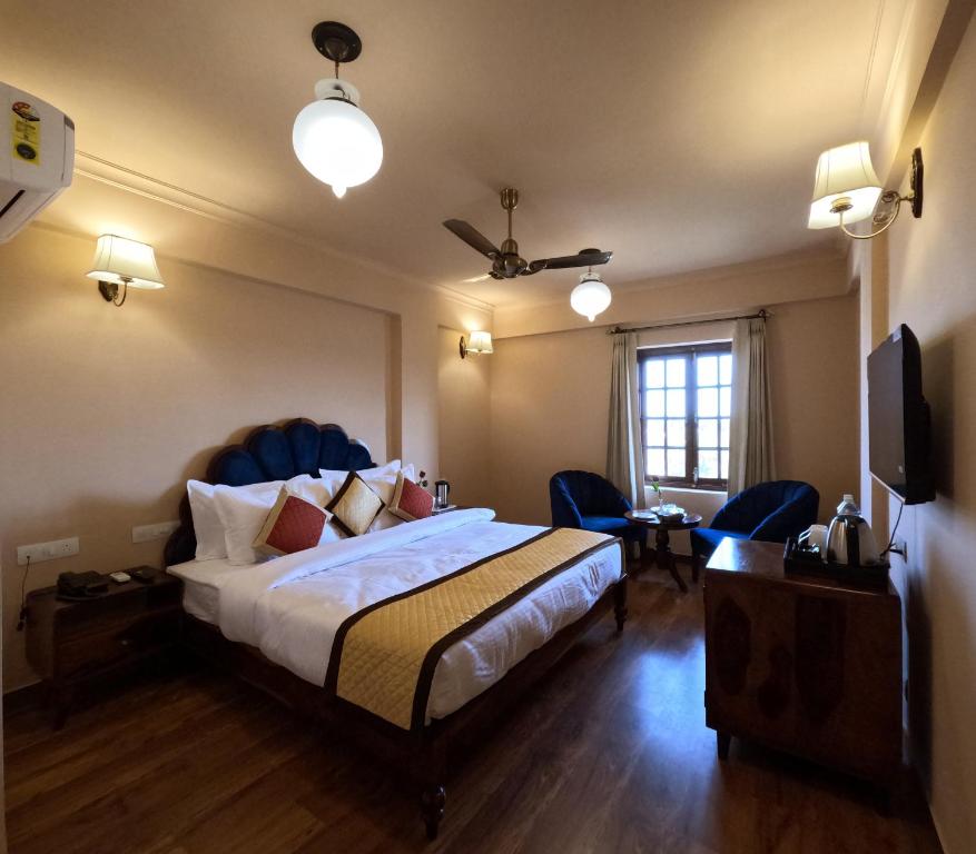 Hotel Chandra Raj Mahal في بيكانير: غرفه فندقيه بسرير وكرسيين