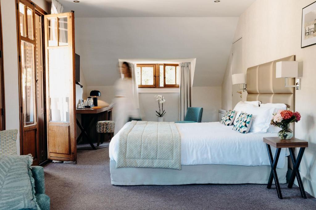 a bedroom with a large white bed and a desk at Hotel Le Cottage Bise in Talloires