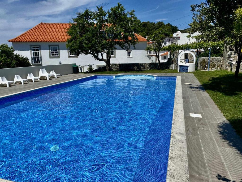 a swimming pool with blue water in front of a house at Solar Laginha - apartamentos, quartos, camas em dormitório in Afife