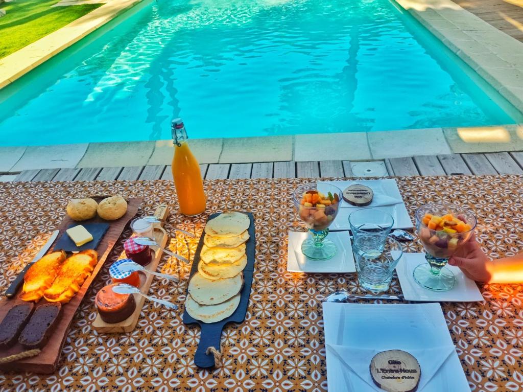 una mesa con comida y bebida junto a una piscina en L'Entre-Nous Carcassonne, en Carcassonne