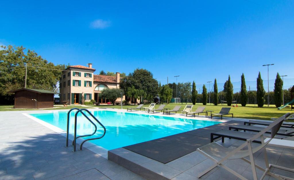 une piscine avec des chaises et une maison en arrière-plan dans l'établissement Casolare La Quercia, à Correzzola