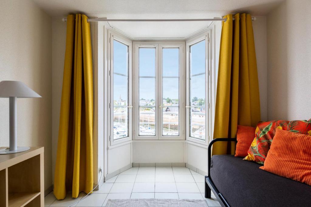 - un salon avec une grande fenêtre et des rideaux jaunes dans l'établissement Résidence Quai des Voiliers 2 - maeva Home - Studio 4 Personnes - Confort - vue sur le Port MAE-7094, à Arzon