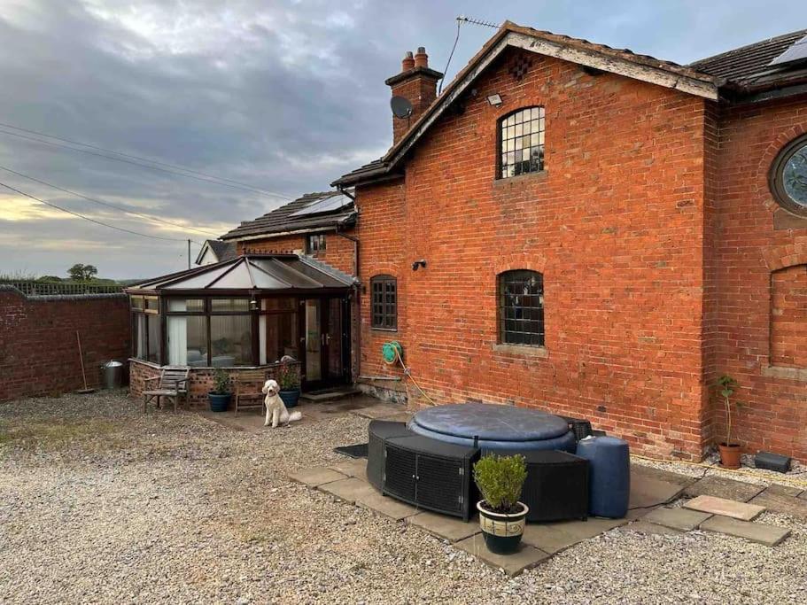 un perro sentado frente a un edificio de ladrillo en The Hurst Coach House, en Stafford