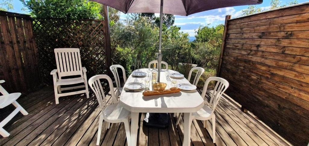 einem weißen Tisch mit Stühlen und einem Sonnenschirm auf einer Terrasse in der Unterkunft Les maisons Le Rouret - maeva Home - Maison 2 Pièces 5 Personnes - Confort MAE-3304 in Grospierres