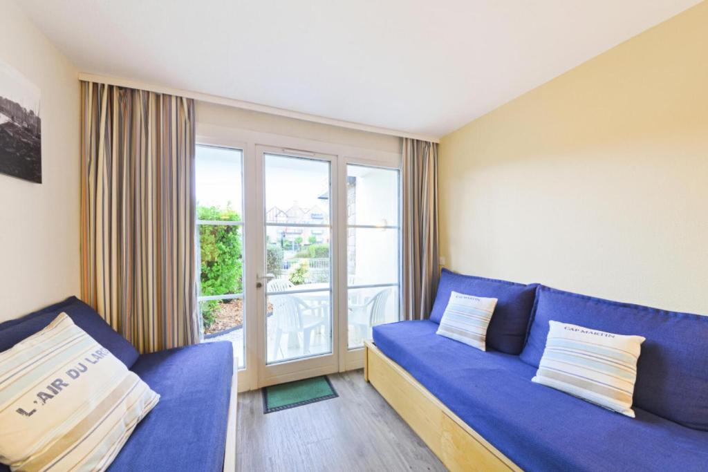 un salon avec un canapé bleu et une grande fenêtre dans l'établissement Résidence Port du Crouesty - maeva Home - Studio 5 Personnes Sélection MAE-2894, à Arzon