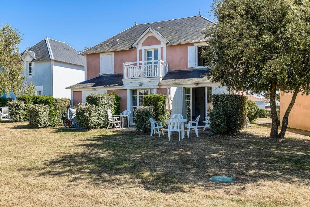 une maison avec des chaises et des tables sur une cour dans l'établissement Les Maisons de Port Bourgenay - maeva Home - Maison 2 pièces 5 personnes - Sélection MAE-0364, à Talmont-Saint-Hilaire