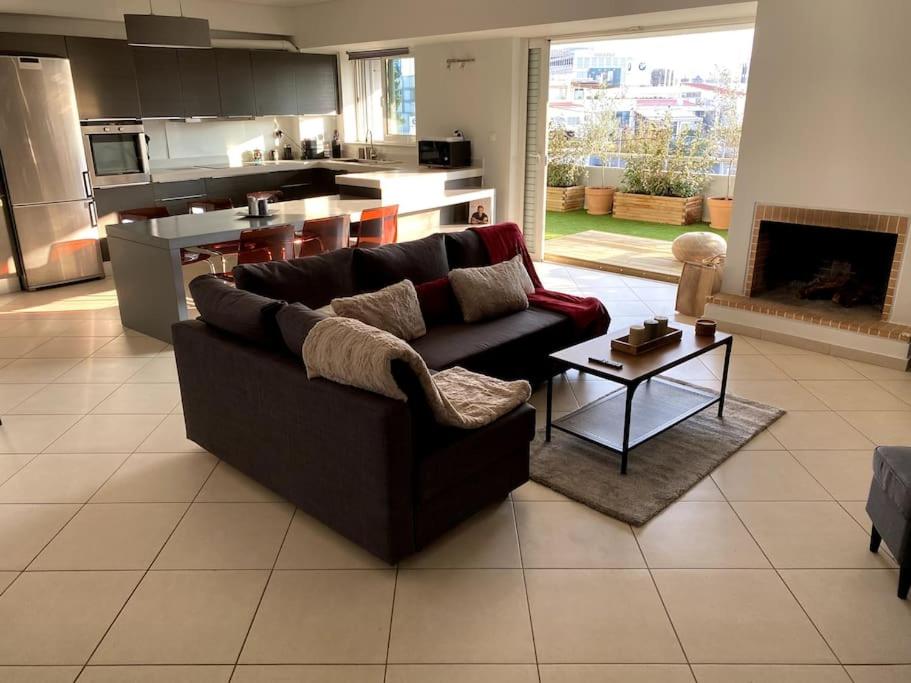 ein Wohnzimmer mit einem Sofa und einer Küche in der Unterkunft Spacious and Sunkissed 3BR & 2 Bathrooms Apartment in Athen