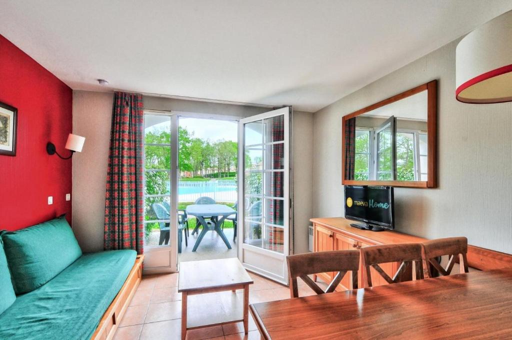 uma sala de estar com um sofá, uma televisão e uma mesa em La résidence du Lac - maeva Home - Maison 3 Pièces 6 Personnes - Confort 764 em Monflanquin