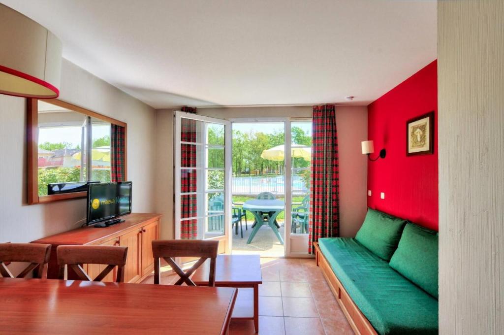 un salon avec un canapé vert et une table dans l'établissement La résidence du Lac - maeva Home - Maison 3 Pièces 6 Personnes - Sélection MAE-5414, à Monflanquin