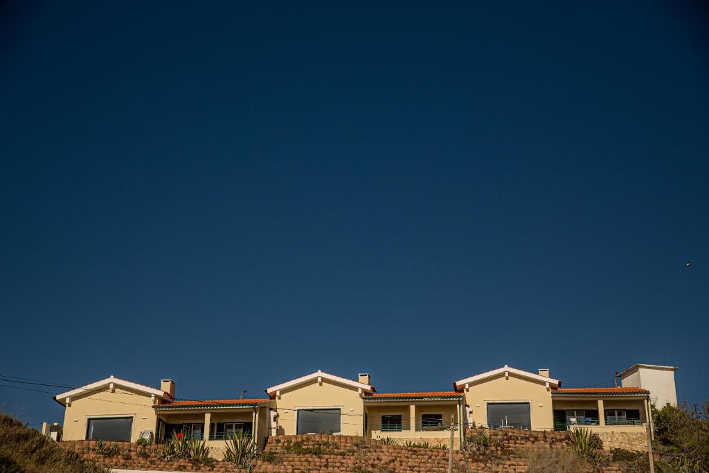 ein großes Haus mit blauem Himmel im Hintergrund in der Unterkunft Agua de Madeiros - Vista do mar in Pedra Do Ouro