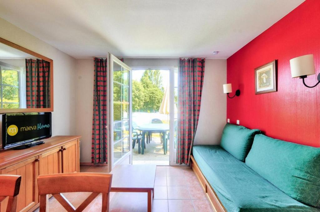 un salon avec un canapé vert et une télévision dans l'établissement La résidence du Lac - maeva Home - Maison 3 Pièces 6 Personnes - Sélection MAE-4524, à Monflanquin