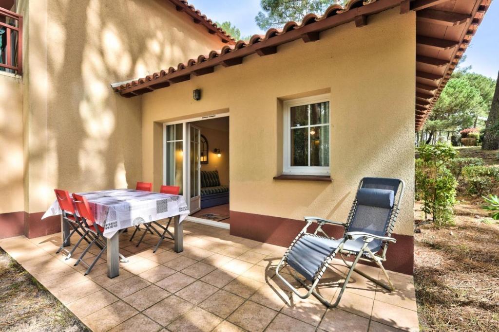 un patio avec une table et des chaises devant une maison dans l'établissement Résidence Lacanau Les Pins - maeva Home - Appartement 2 pièces 6 personnes Sélection MAE-9142, à Lacanau
