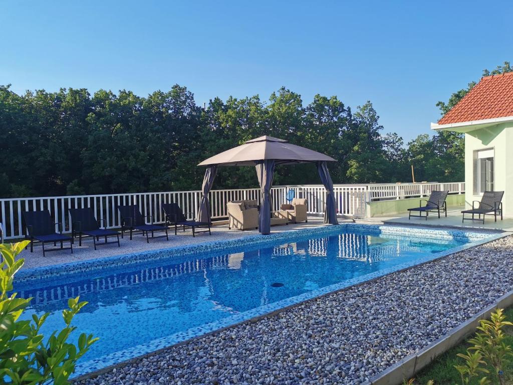 a swimming pool with a gazebo next to a house at Kuća za odmor -FourM in Novak