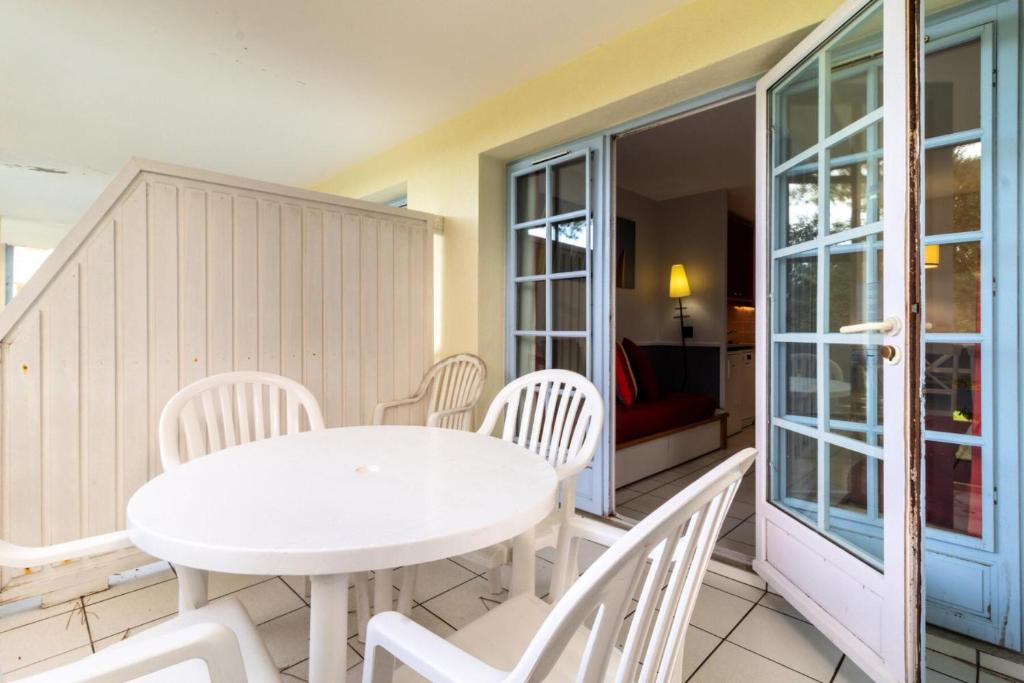 une table blanche et des chaises sur un balcon dans l'établissement Village Moliets - maeva Home - Appartement 2 pièces 4 personnes - Confort MAE-9764, à Moliets-et-Maa