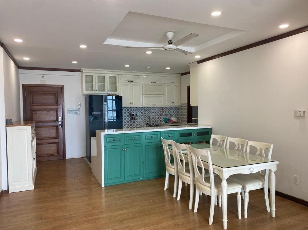 a kitchen with green cabinets and a table and chairs at Spacious Apartment with 3-bedroom in District 7 in Ho Chi Minh City