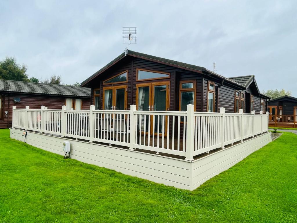 a wooden house with a white fence in the yard at Crystal Lodge with Hot Tub in Malton