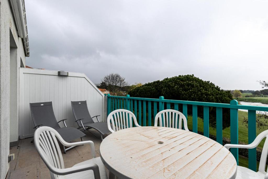 une table et des chaises en bois assises sur un balcon dans l'établissement Résidence Port Bourgenay - maeva Home - Appartement 2 pièces 6 personnes - Sélection MAE-6314, à Talmont-Saint-Hilaire