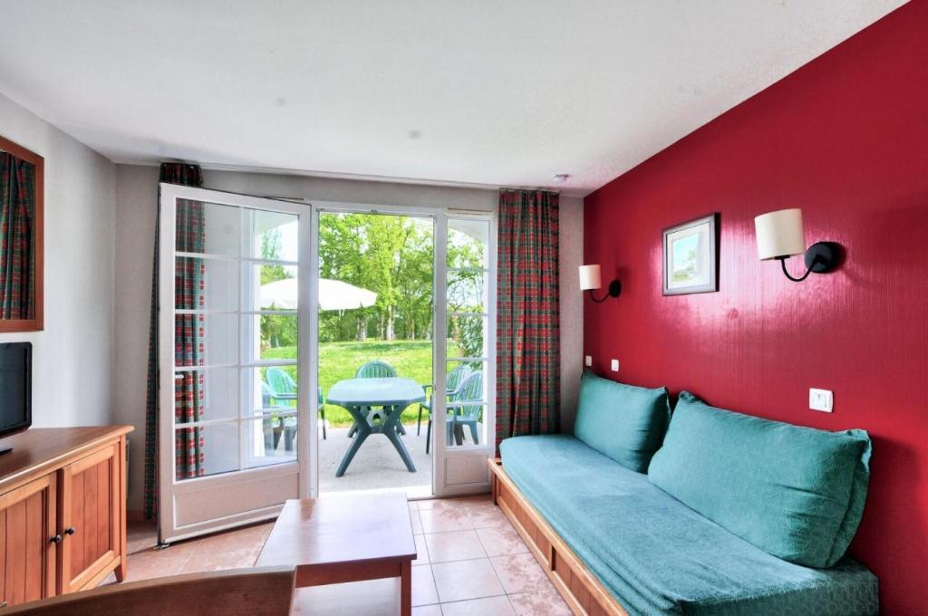 un salon avec un canapé bleu et une terrasse dans l'établissement La résidence du Lac - maeva Home - Maison 3 pièces 6 personnes - Sélection MAE-5434, à Monflanquin
