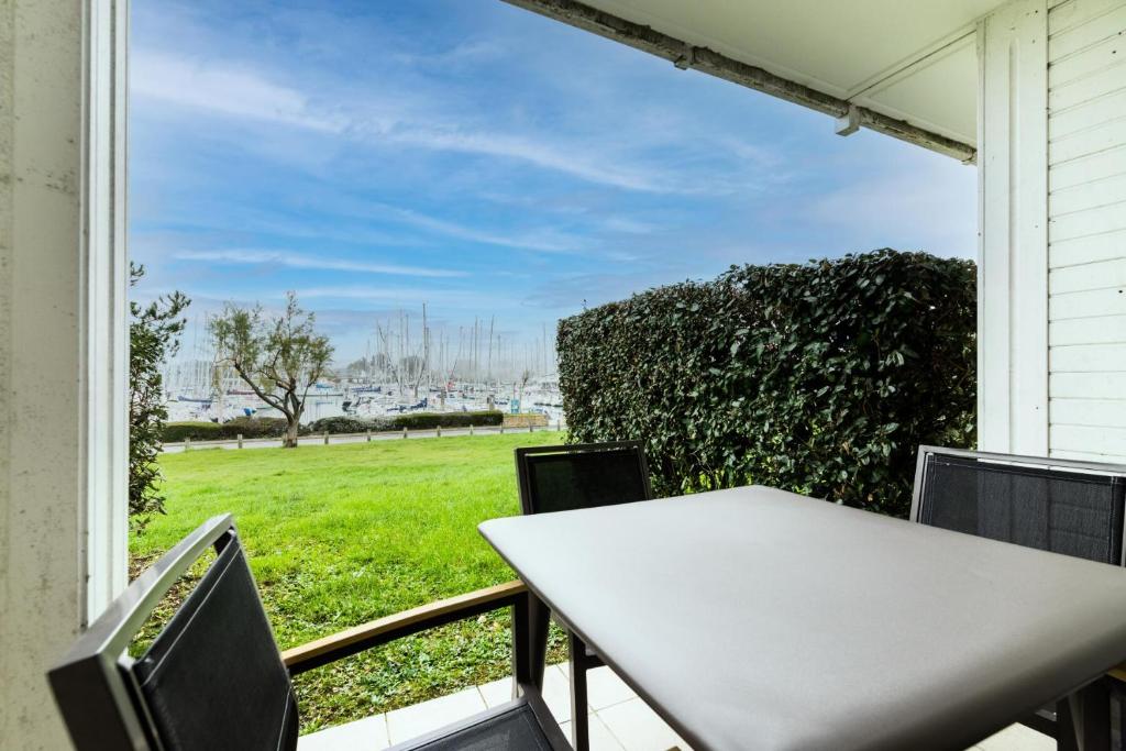 d'une table et de chaises sur un balcon avec vue sur un champ. dans l'établissement Port du Crouesty Cap'Océan - maeva Home - Appartement 2 pièces 5 personnes - Sélection - vue sur le Port MAE-0844, à Arzon