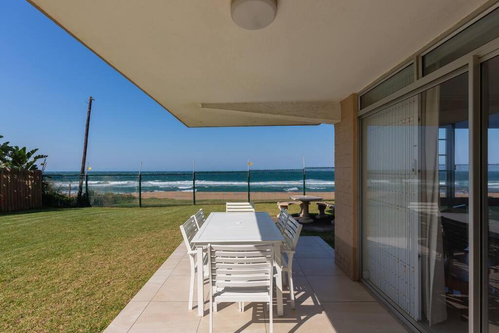 een tafel en stoelen op een patio met uitzicht op de oceaan bij 7 Kenwyn On Sea in Ballito