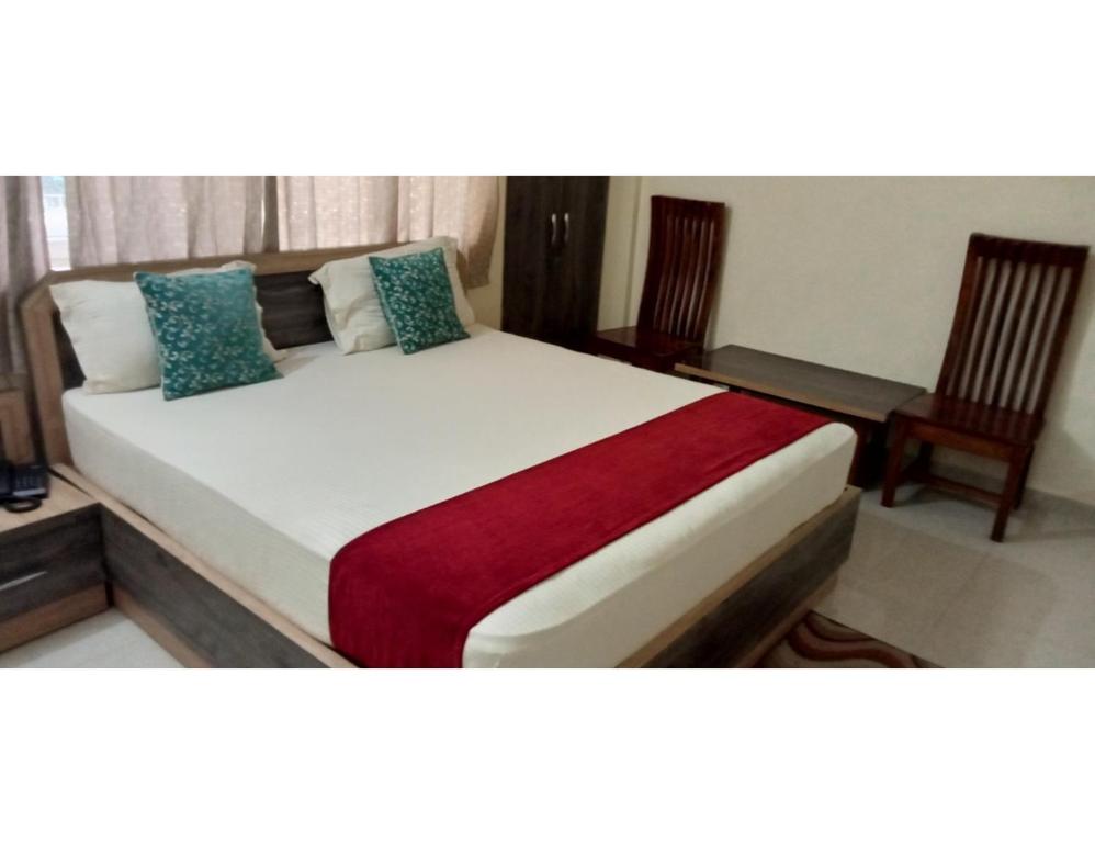 1 dormitorio con 1 cama grande y 2 sillas en Hotel Nageshwar Palace, Rajgir en Rajgir