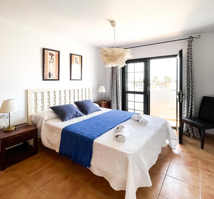 Laguna Home by Best Holidays Fuerteventura في كوراليخو: غرفة نوم بسرير كبير وملاءات زرقاء وبيضاء