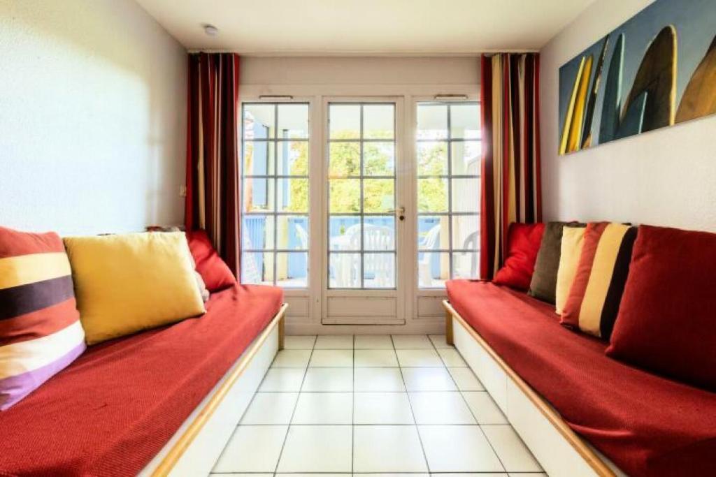 - un salon avec deux canapés rouges et une fenêtre dans l'établissement Village Moliets - maeva Home - Appartement 2 pièces 4 personnes - Confort MAE-6784, à Moliets-et-Maa