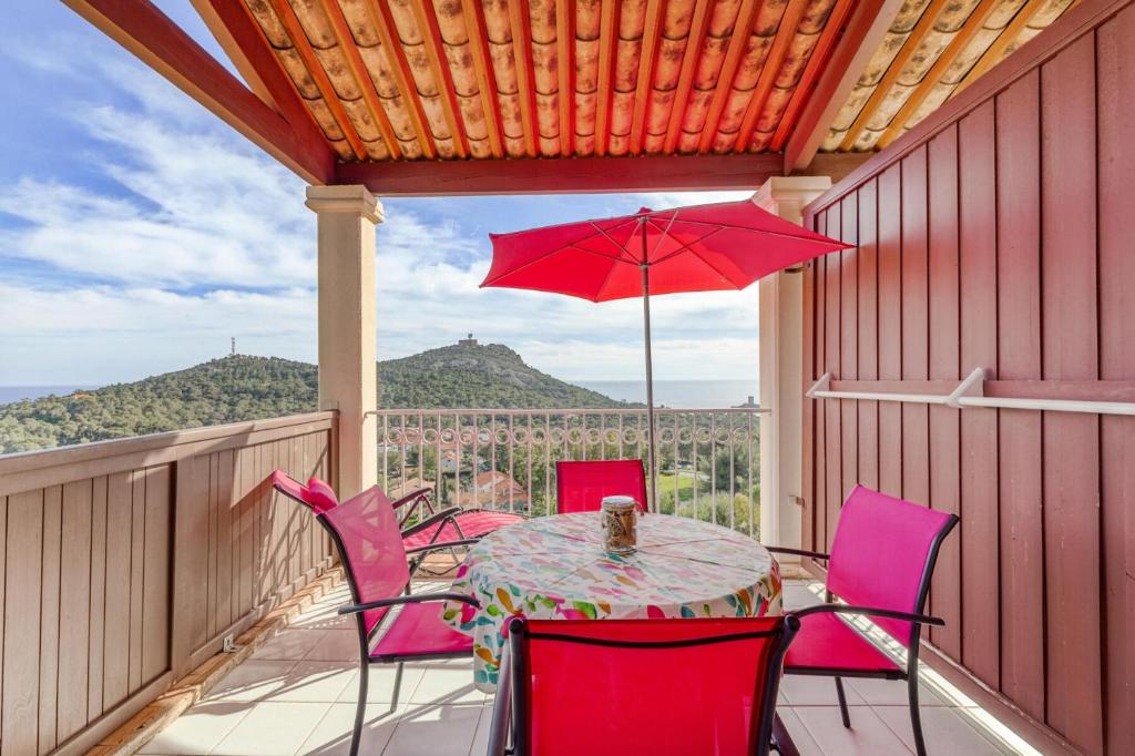 d'une table avec des chaises et un parasol rouge sur le balcon. dans l'établissement Résidence le Hameau de Cap Esterel - maeva Home - Appartement 2 pièces 4 personnes - Sélection MAE-0594, à Saint-Raphaël