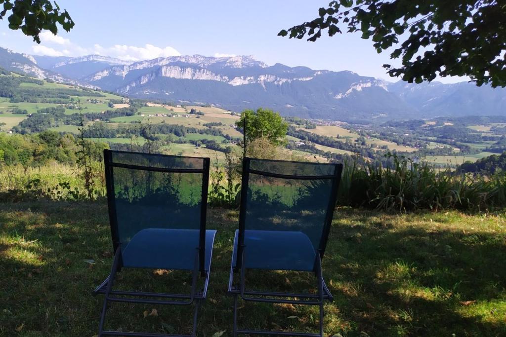 two chairs sitting on top of a field with mountains at Chartreuse in Saint-Franc