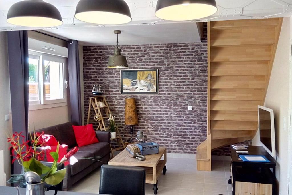 un salon avec un canapé et un mur de briques dans l'établissement Ty Tiegezh Gîte TiDastum, à Créhen