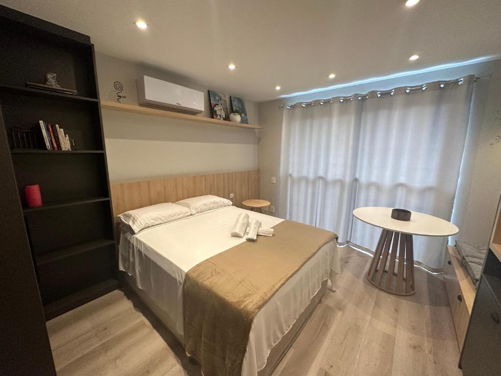 a bedroom with a bed and a table in it at Loft no Bairro Auxiliadora in Porto Alegre