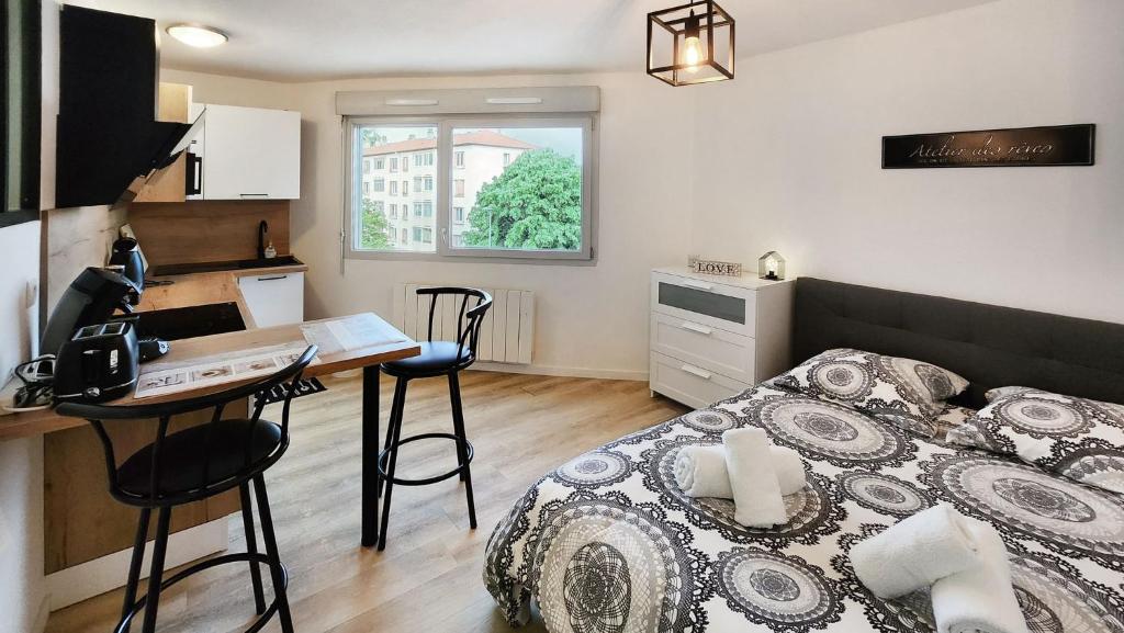 1 dormitorio con cama, escritorio y cocina en Studio cosy élégant, en Villeurbanne