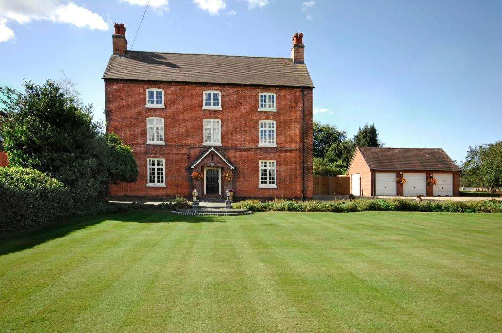 a large red brick house with a large grass yard at Blackgreaves Farmhouse in Lea Marston