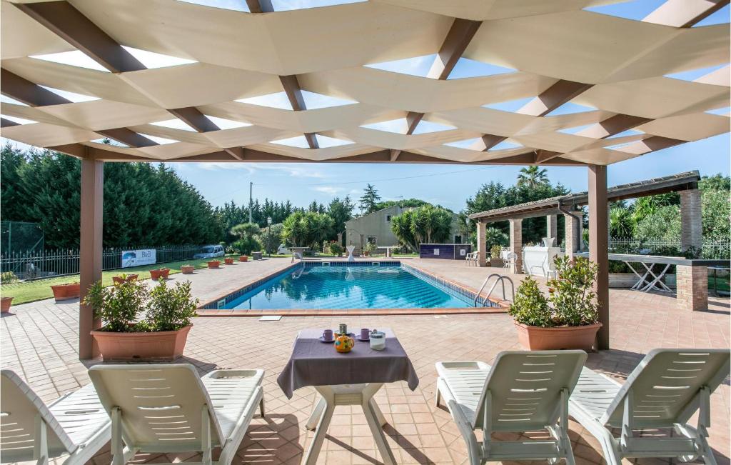 a patio with a table and chairs and a pool at Beautiful Home In Grammichele With Kitchenette in Grammichele