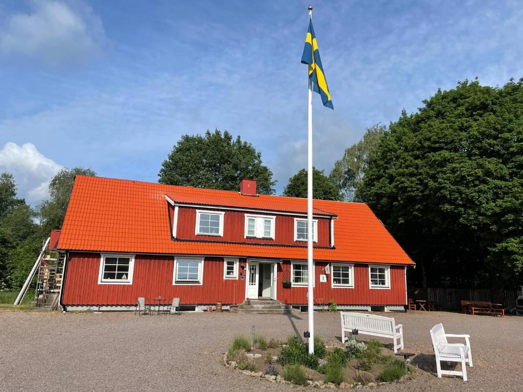 a red house with an orange roof and a flag at Sjökaptensgården Bed & Breakfast in Åsljunga