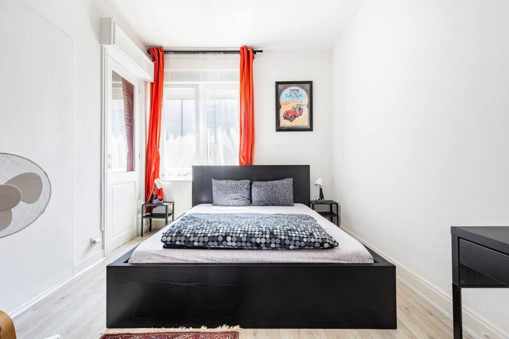 - une chambre avec un lit noir et des rideaux orange dans l'établissement Chambres en appartements partagés, à Liège