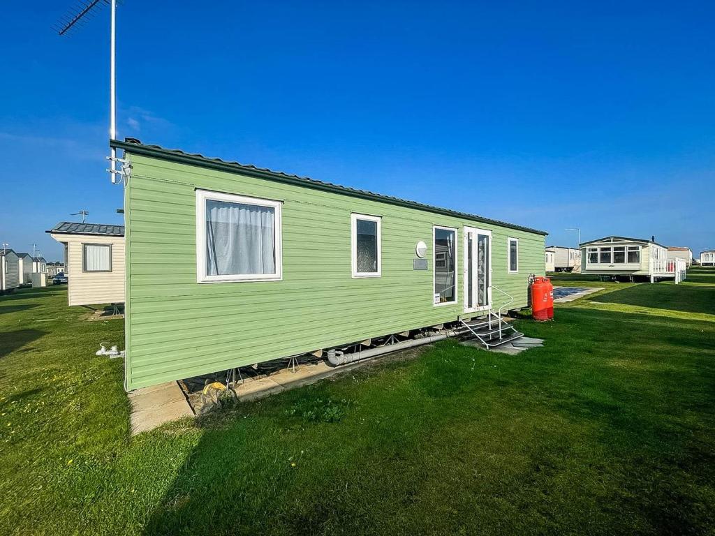 una casita verde en un campo de hierba en Lovely 8 Berth Caravan Nearby Scratby Beach In Norfolk Ref 50021f, en Great Yarmouth