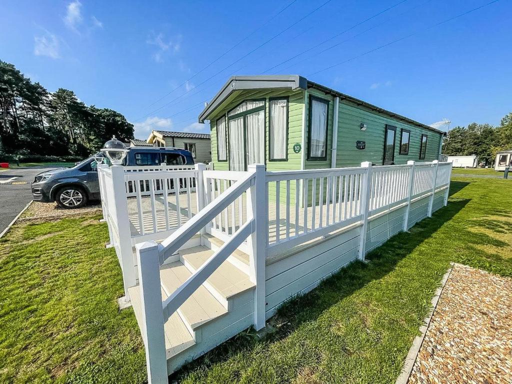 a green and white house with a white fence at Lovely 6 Berth Caravan At Caldecott Hall Country Park, Norfolk Ref 91010c in Great Yarmouth